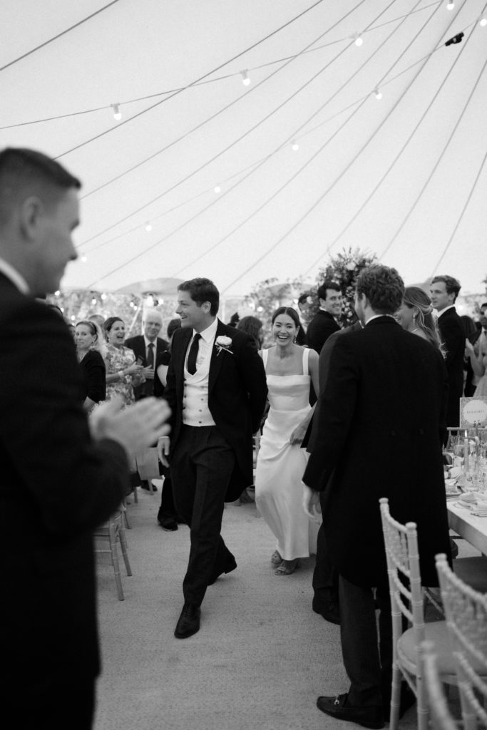 Bride and groom walking to their table at a marquee wedding in the Cotswolds