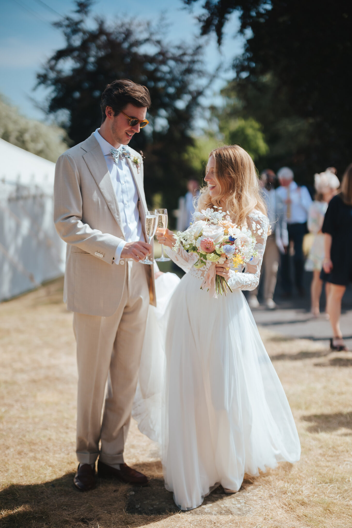 Bride and groom drinking champagne outside their wedding marquee